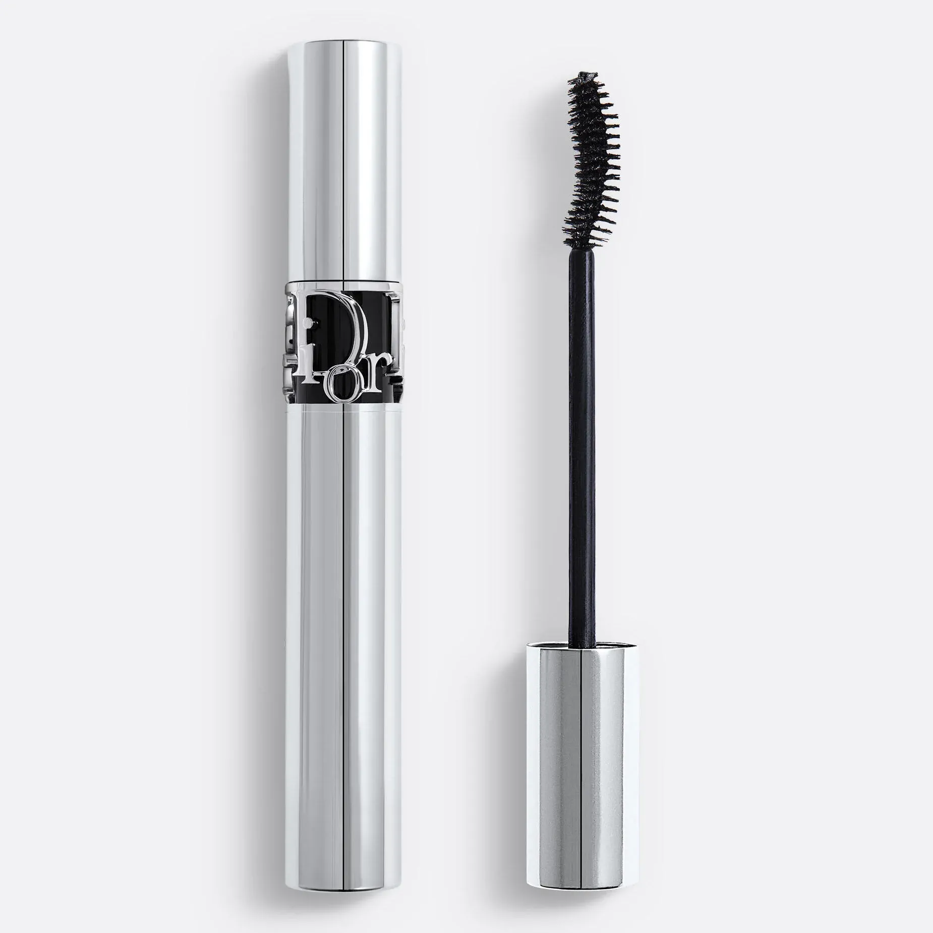A silver tube of Dior mascara, next to the wand of the mascara, against a light-gray background
