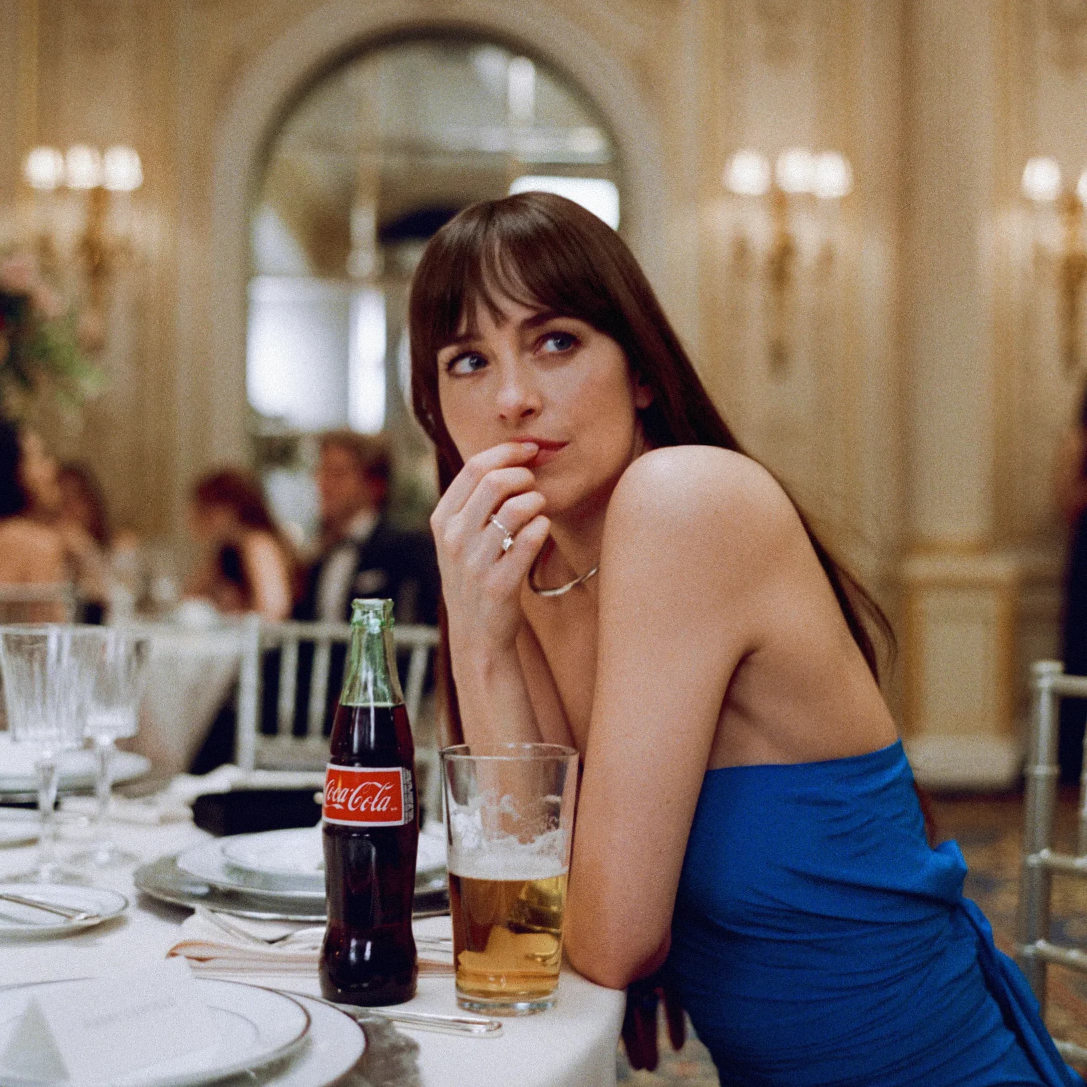 Dakota Johnson sitting at a table in a fine dining hall 