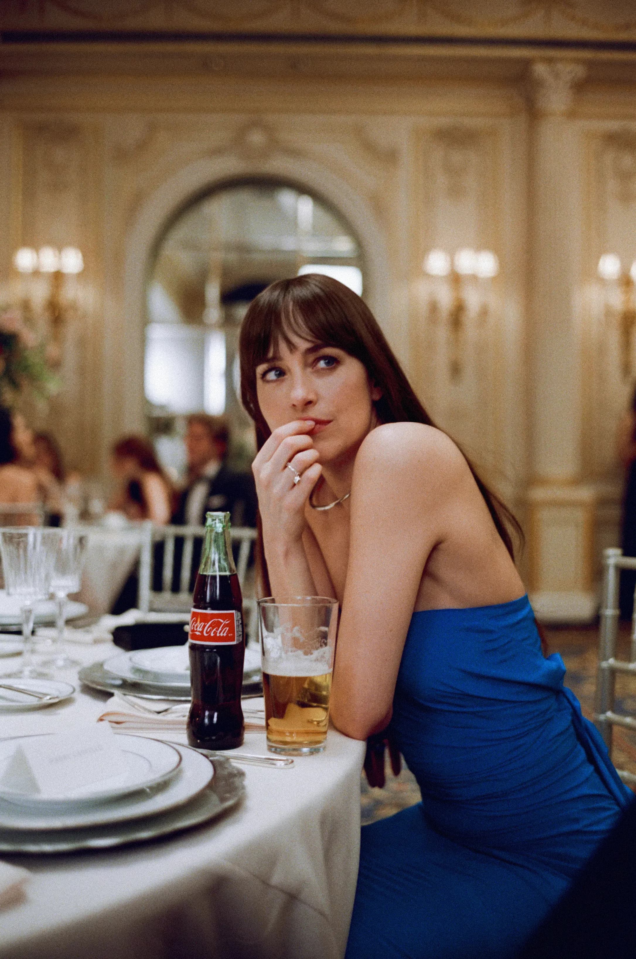 Dakota Johnson sitting at a table in a fine dining hall 