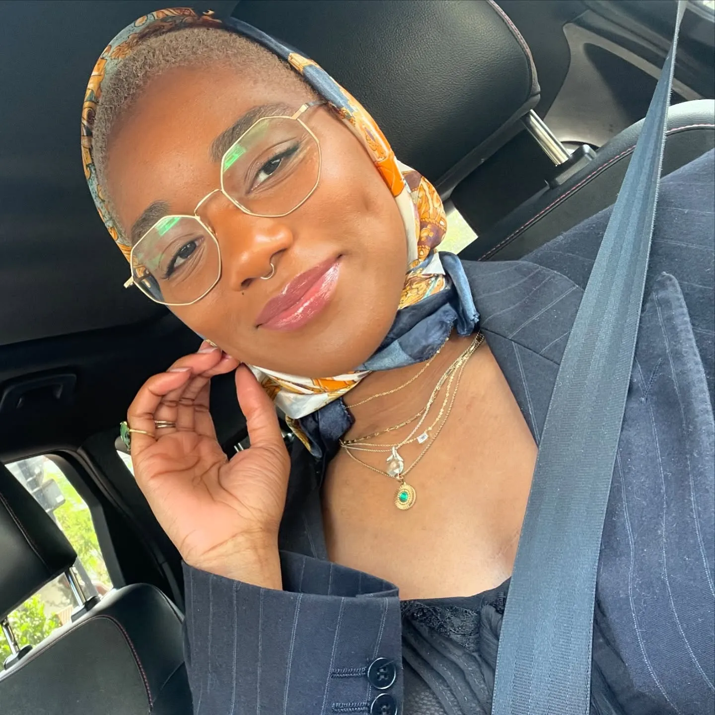 A selfie taken by British actress Rachel Adedeji in her car, wearing glasses and a headscarf.