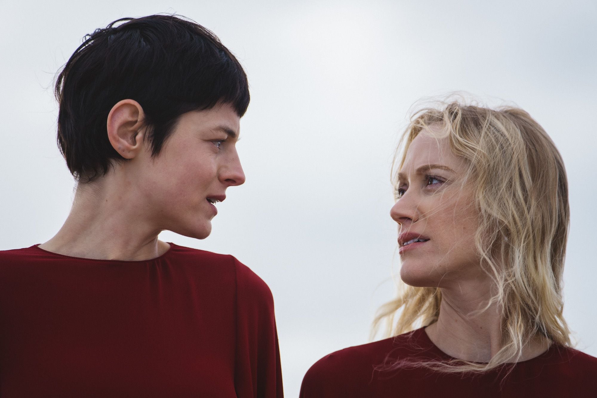 Close up of Emma Corrin and Maika Monroe looking at each other outside in "100 Nights of Hero."