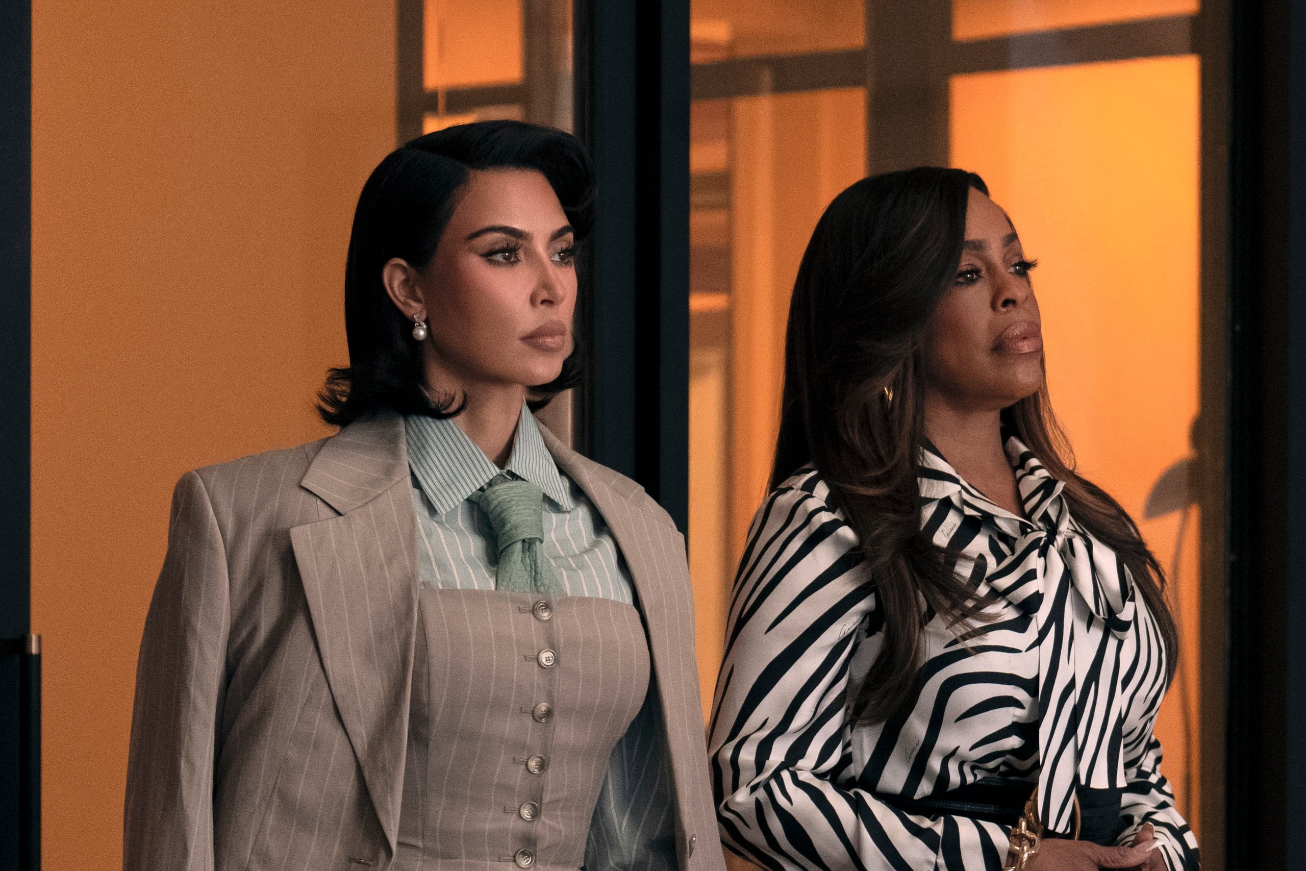 Kim Kardashian and Niecy Nash stand in a conference room in front of a table in a still from Hulu's All's Fair.