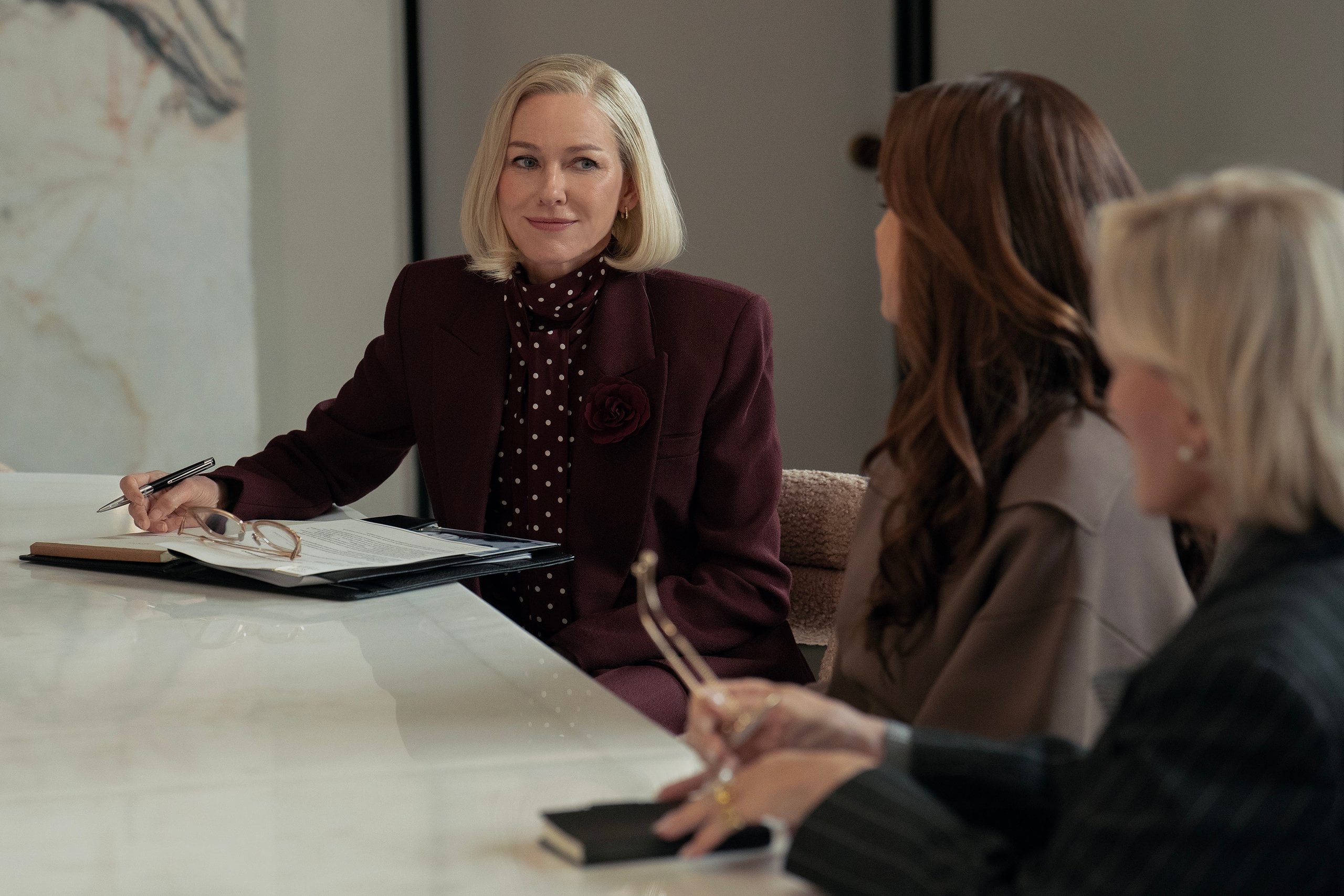 Actor Naomi Watts sits in a conference room speaking to two clients in a still from All's Fair.