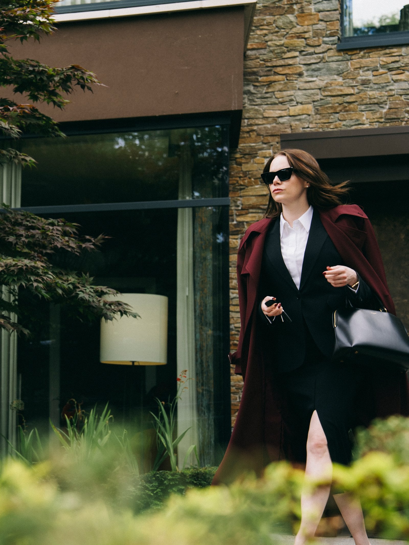 Emma Stone exits a fancy house on her way to her car in a still from "Bugonia."