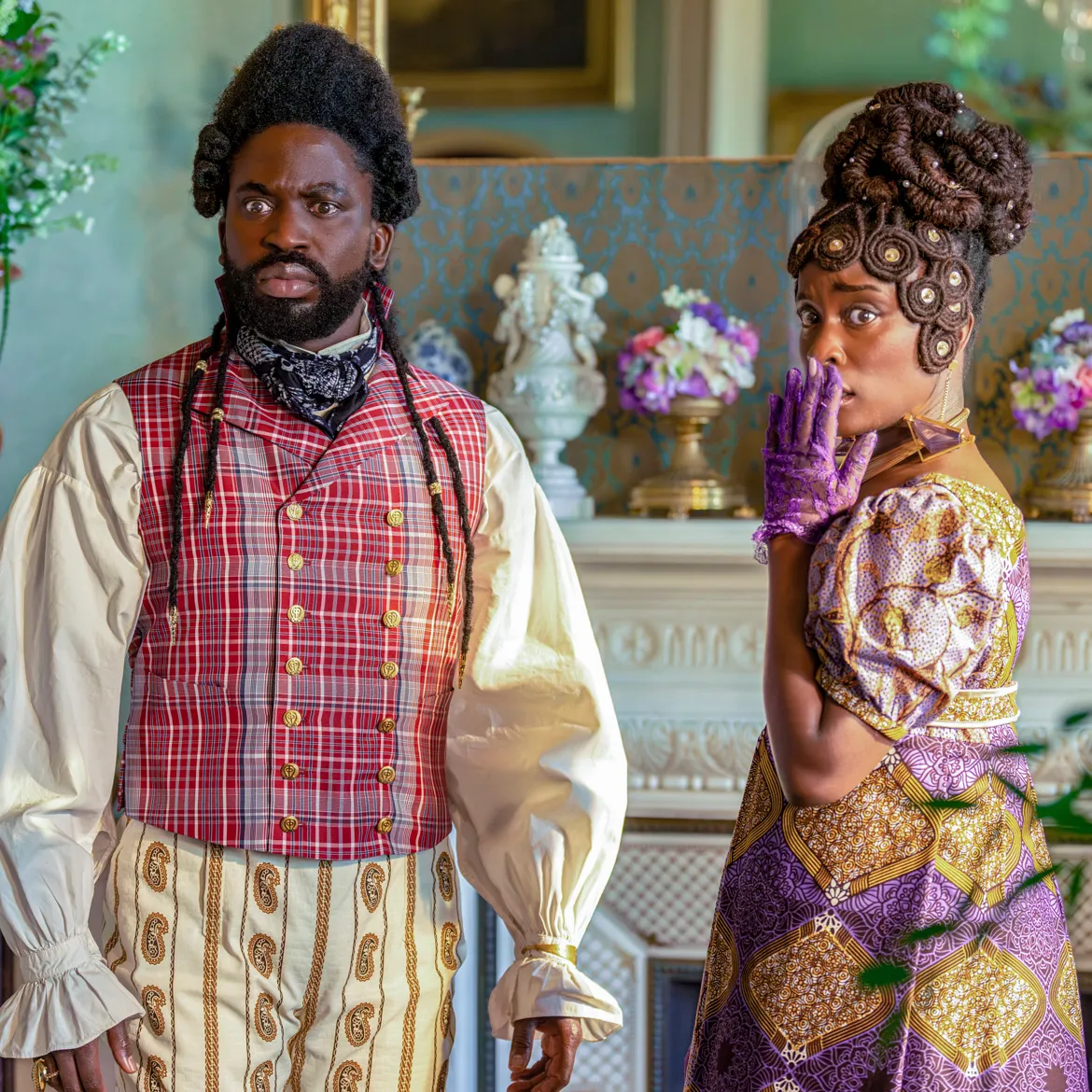 Actors Adjani Salmon and Babirye Bukilwa stand together dressed in Regency-era clothing, in a still from "Dreaming Whilst Black."