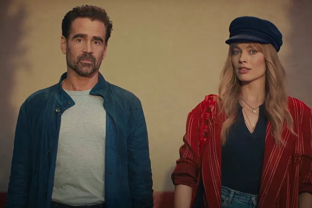Actors Colin Farrell and Margot Robbie stand next to one another against a beige background in a still from "A Big Bold Beautiful Journey."