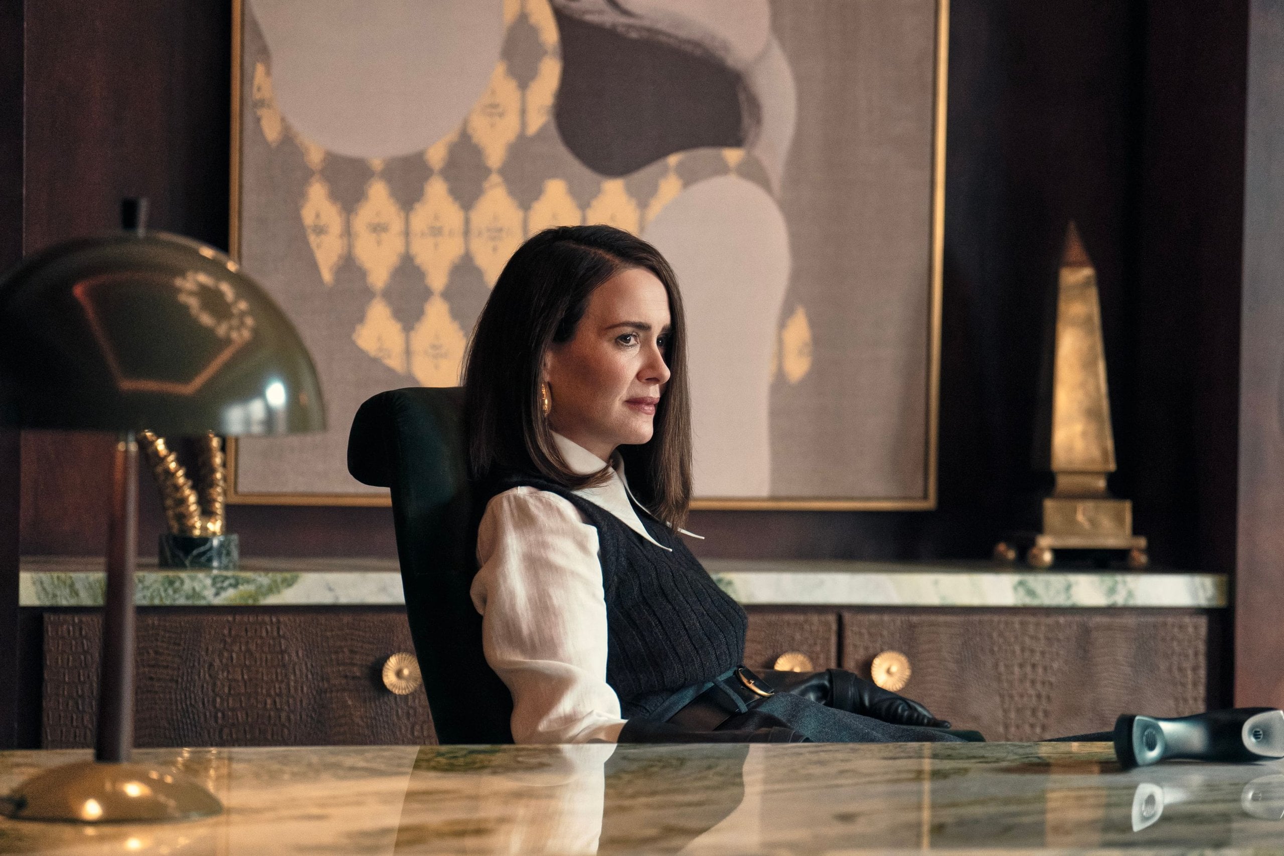 Actor Sarah Paulson sits at a desk in a fancy office in a still from Hulu's All's Fair show.