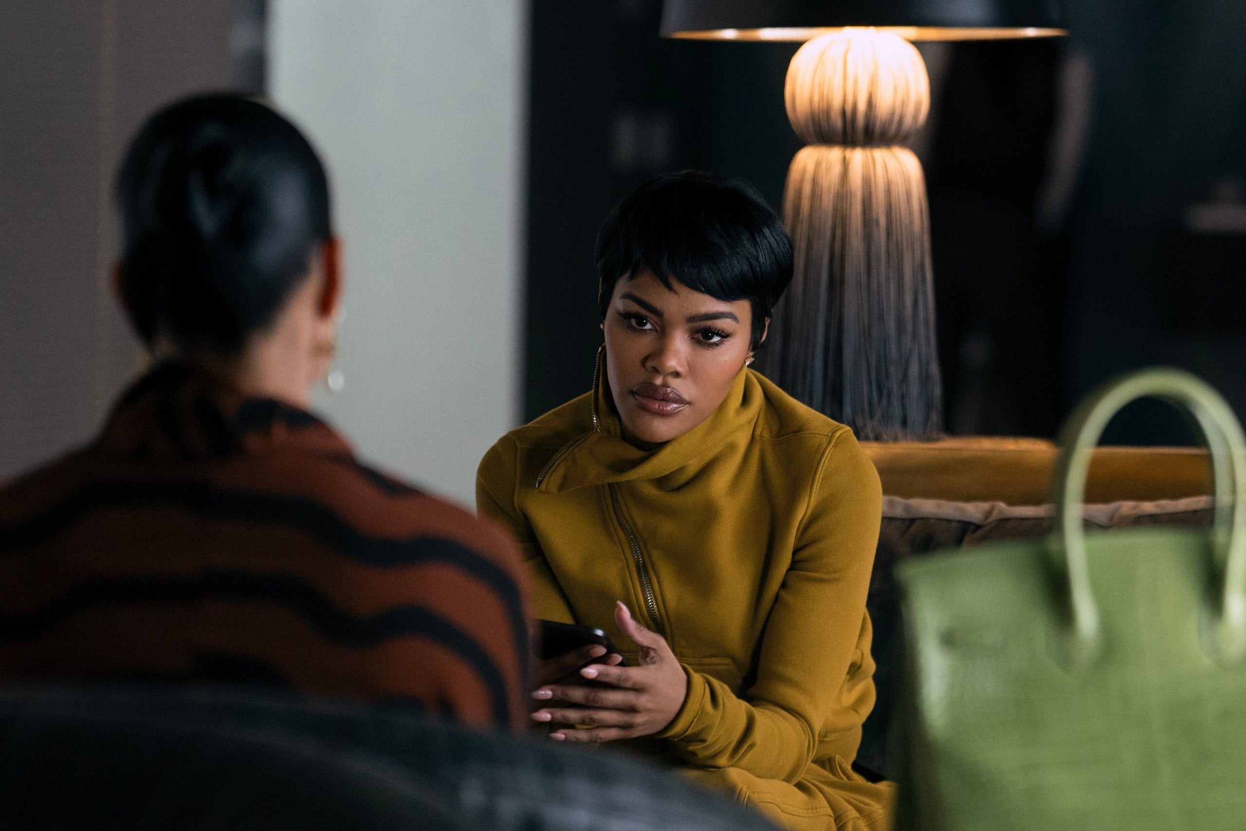 Teyana Taylor sit across from someone on a couch in a still from Hulu's All's Fair.