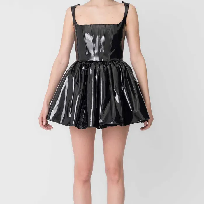 girl in black PVC mini dress against a gray background