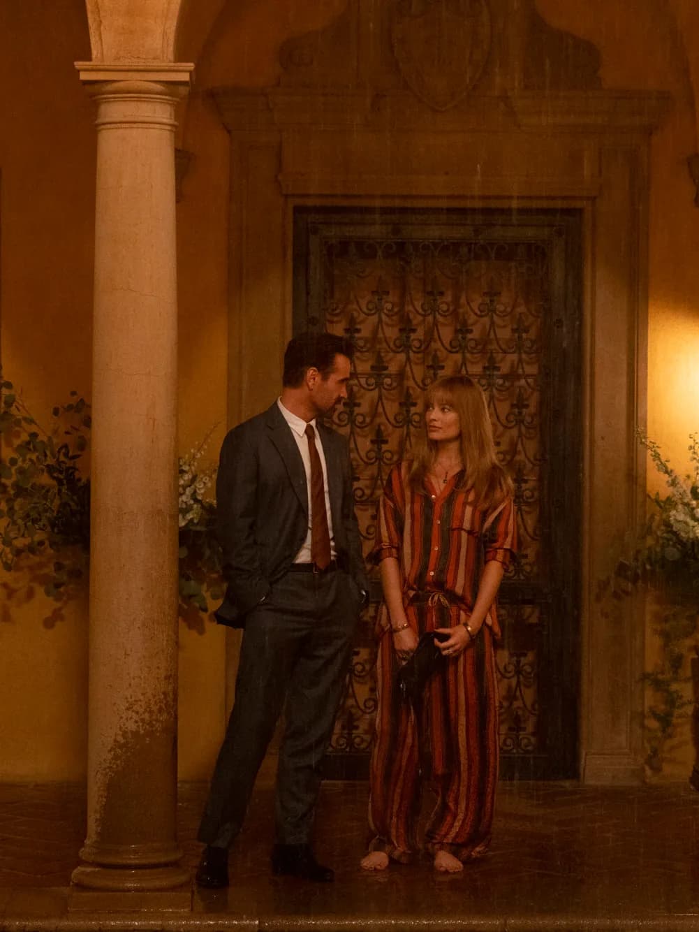 Actors Colin Farrell and Margot Robbie stand in front of a fancy house in a still from "A Big Bold Beautiful Journey".
