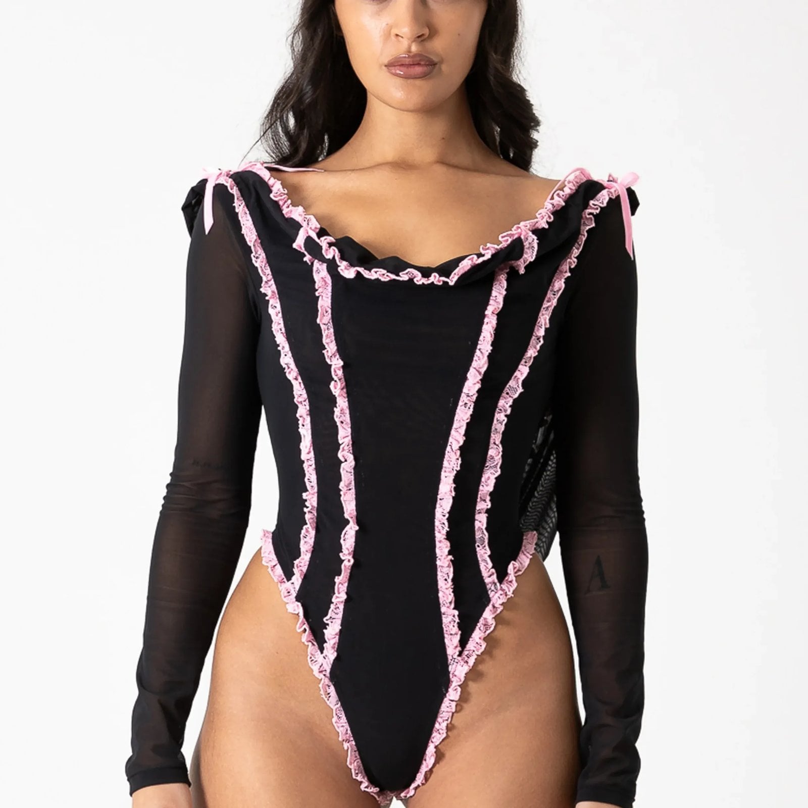 A model in a black and pink-ruffled body suit against a white background
