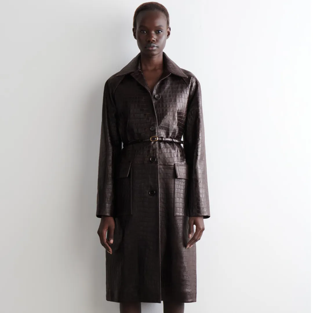 A model wears a faux-croc embossed coat from COS in dark brown