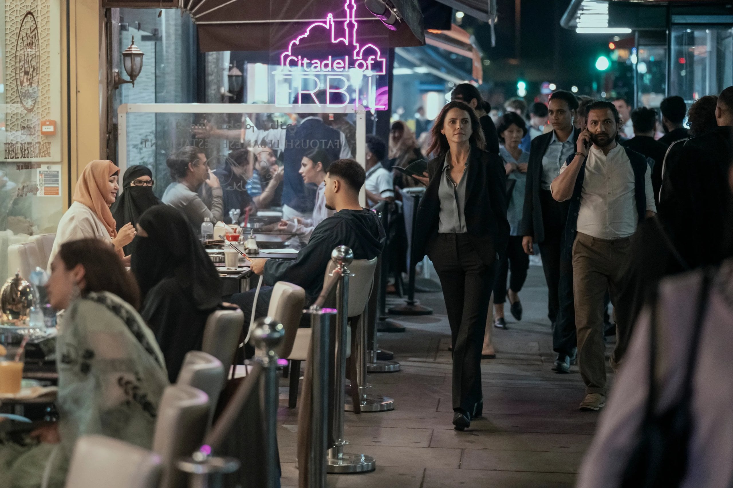 Keri Russell walks along a crowded street at night in a still from The Diplomat.