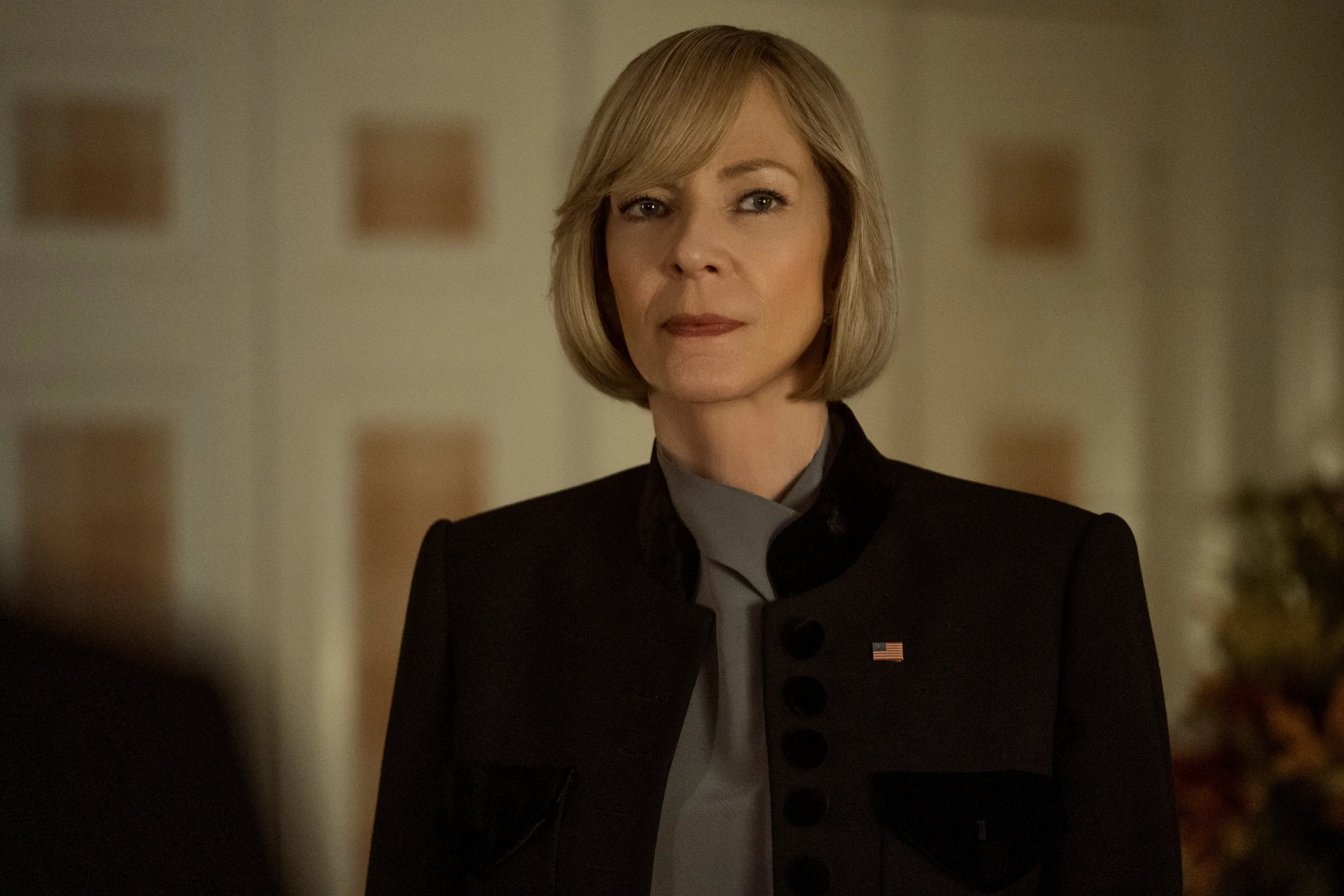 Allison Janney wears a suit and American flag pin in a still from The Diplomat.