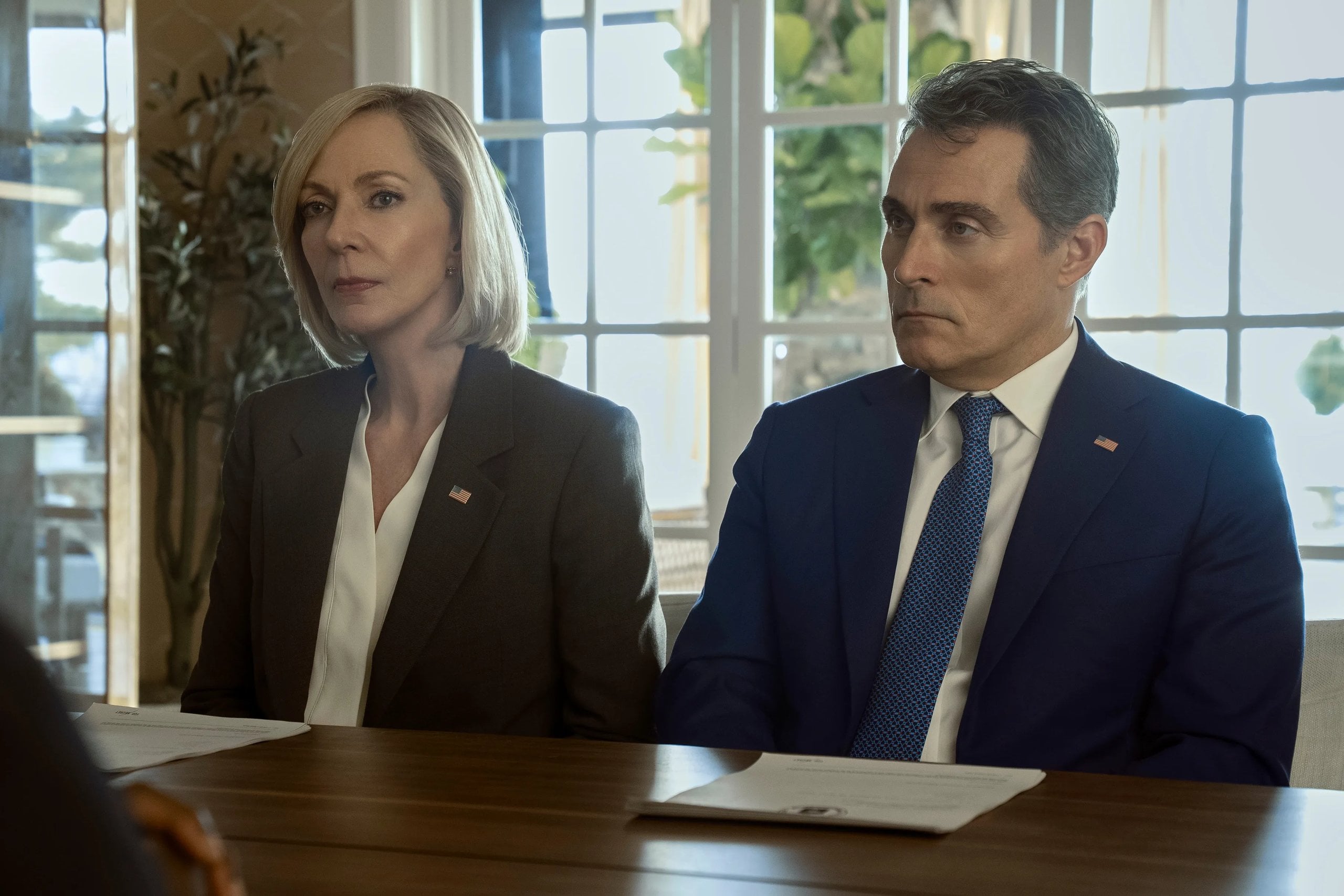 Allison Janney and Rufus Sewell sit next two each other at a desk in a still from The Diplomat.