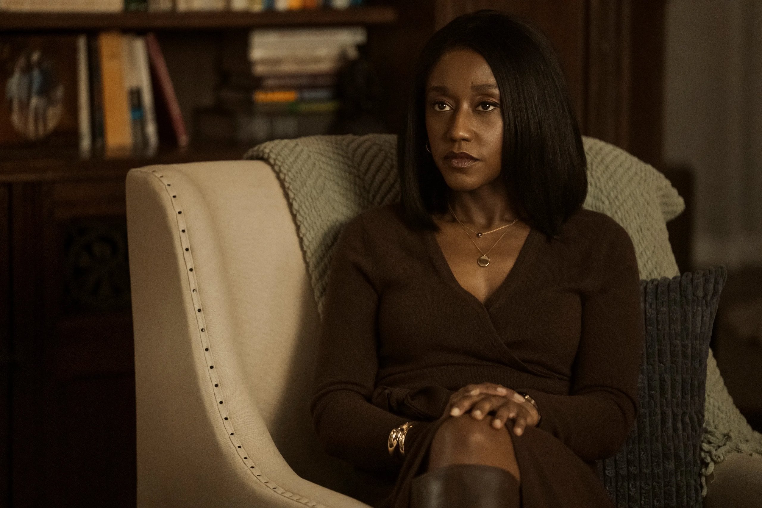 Nana Mensah sits on a chair with her hands on her knees in a still from The Diplomat.