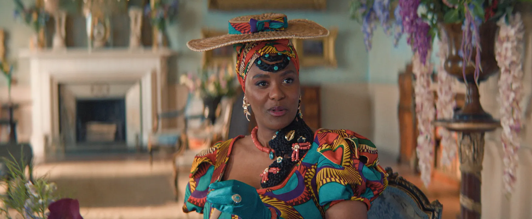 Actress Eshe Ashante sits on a couch wearing Regency-era clothing in a Nigerian print in a still from "Dreaming Whilst Black."