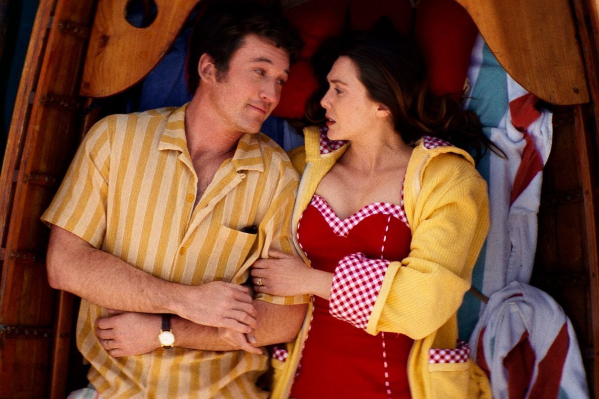 Actors Miles Teller and Elizabeth Olsen lay down in a row boat, staring at each other in a still from Eternity.