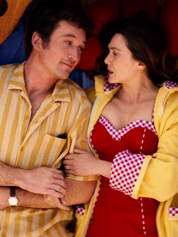 Actors Miles Teller and Elizabeth Olsen lay down in a row boat, staring at each other in a still from Eternity.