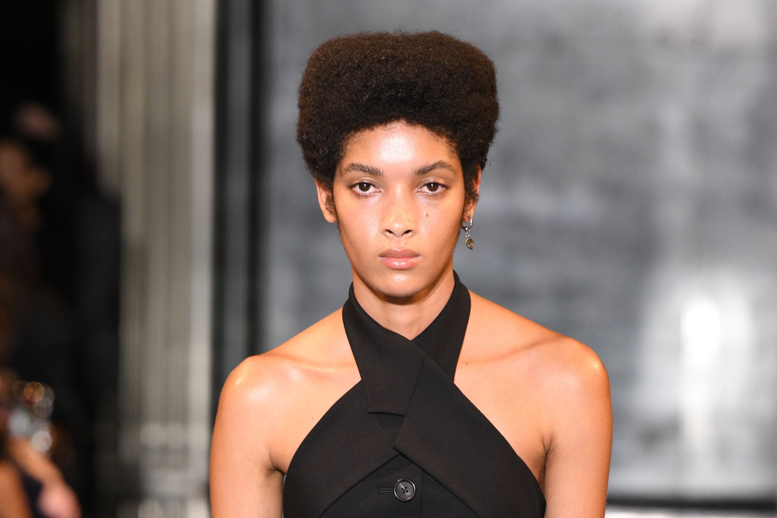A model walks the runway during the Monse fall/winter 2024 show in a black dress with cross-cross neckline.