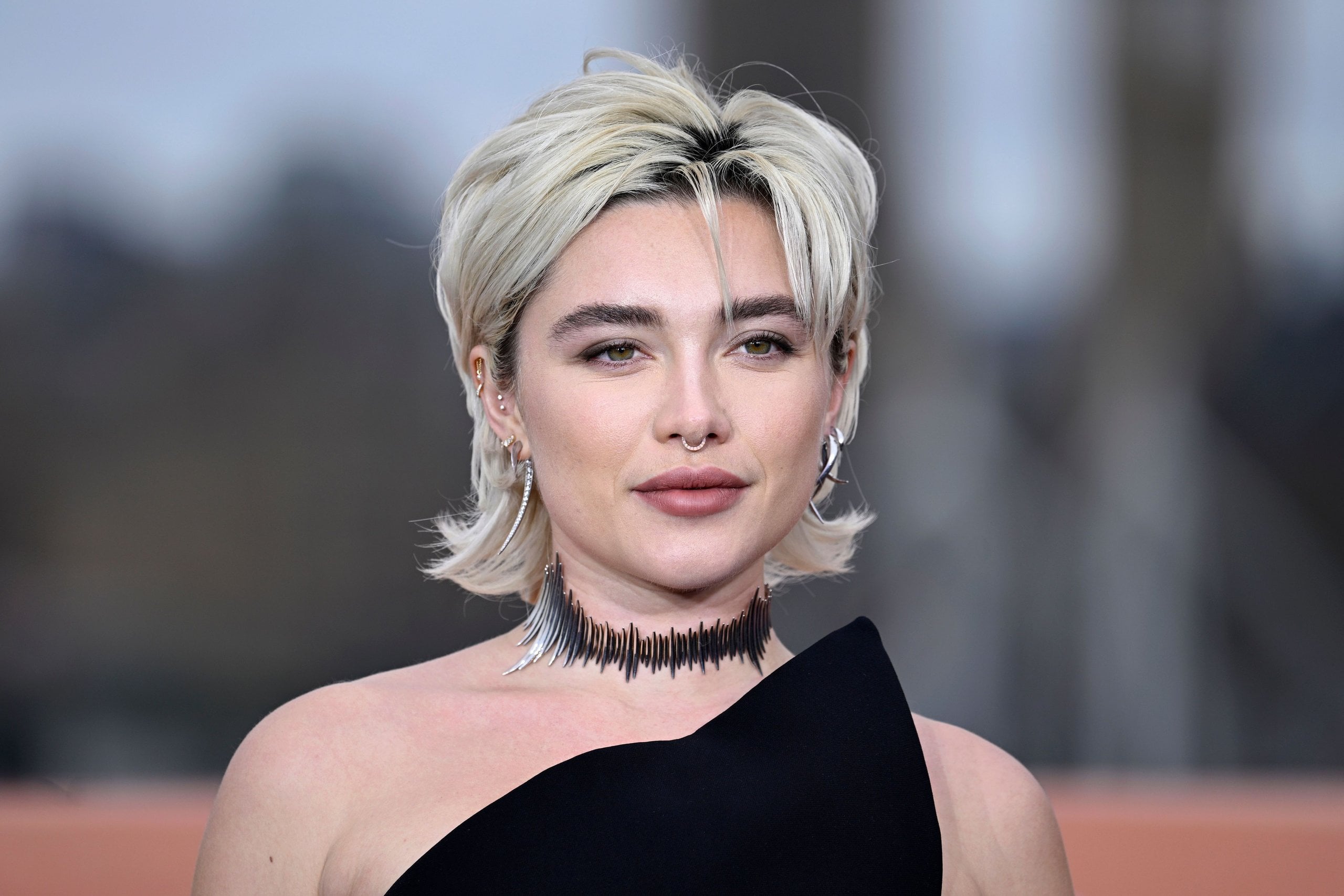Florence Pugh attends the photocall for "Dune: Part Two" at IET London on February 14, 2024 in a black dress with a bleached blonde mullet.