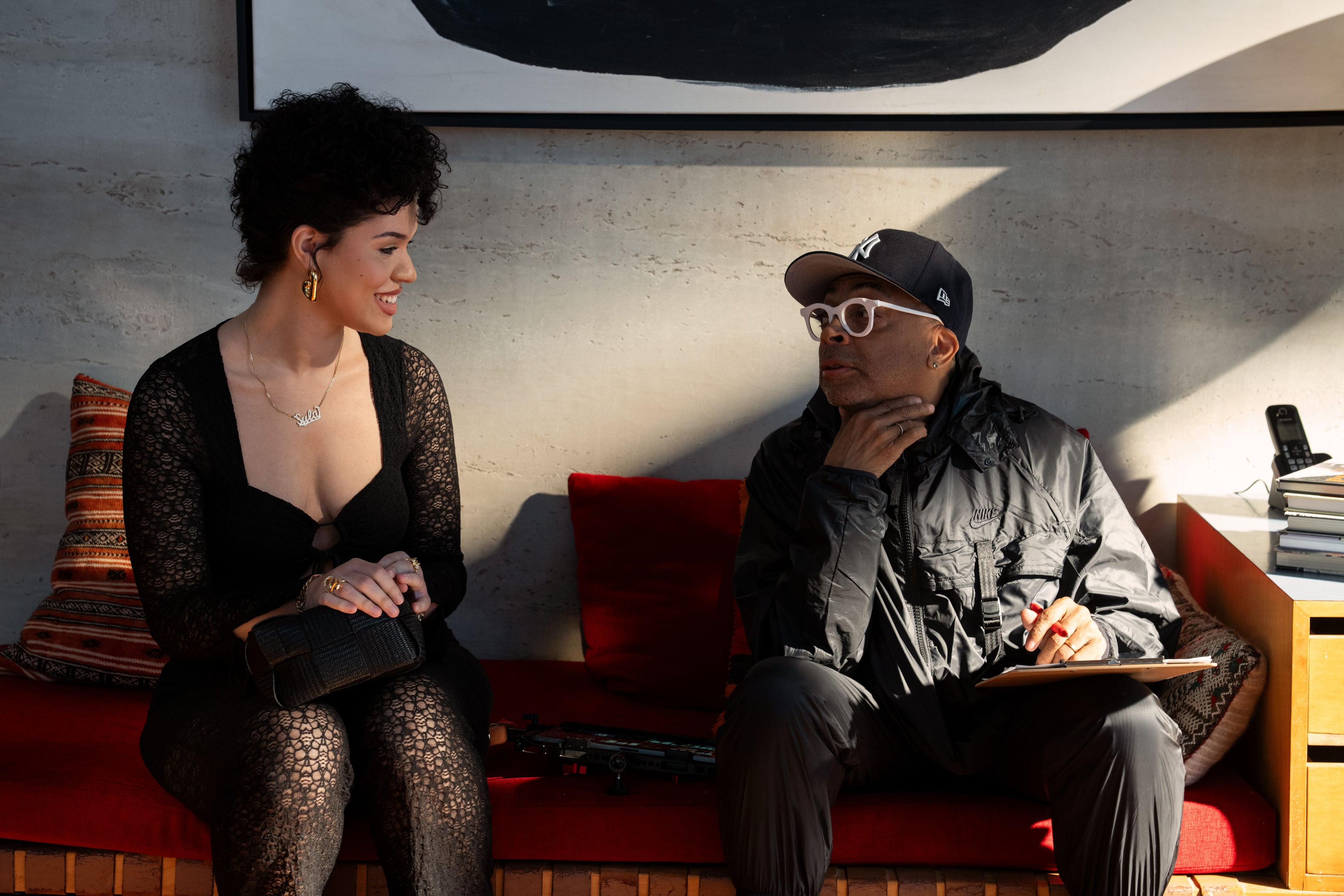 Actress Aiyana-Lee and director Spike Lee, each wearing black, sit on a couch on set of the film "Highest 2 Lowest."