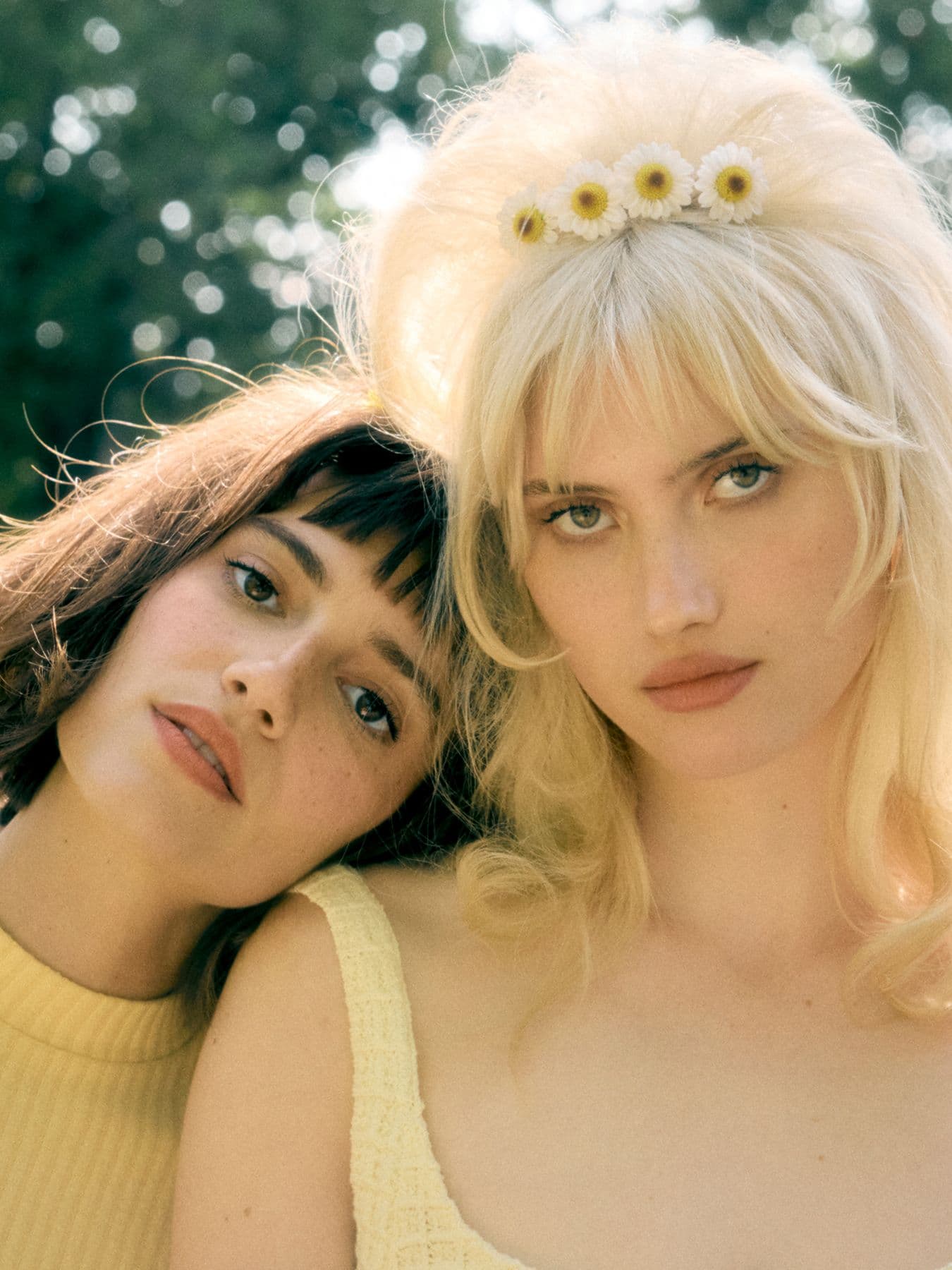 Two models, one blonde, one brunette, dressed in in yellow look. into the camera with their hair beautifully styled