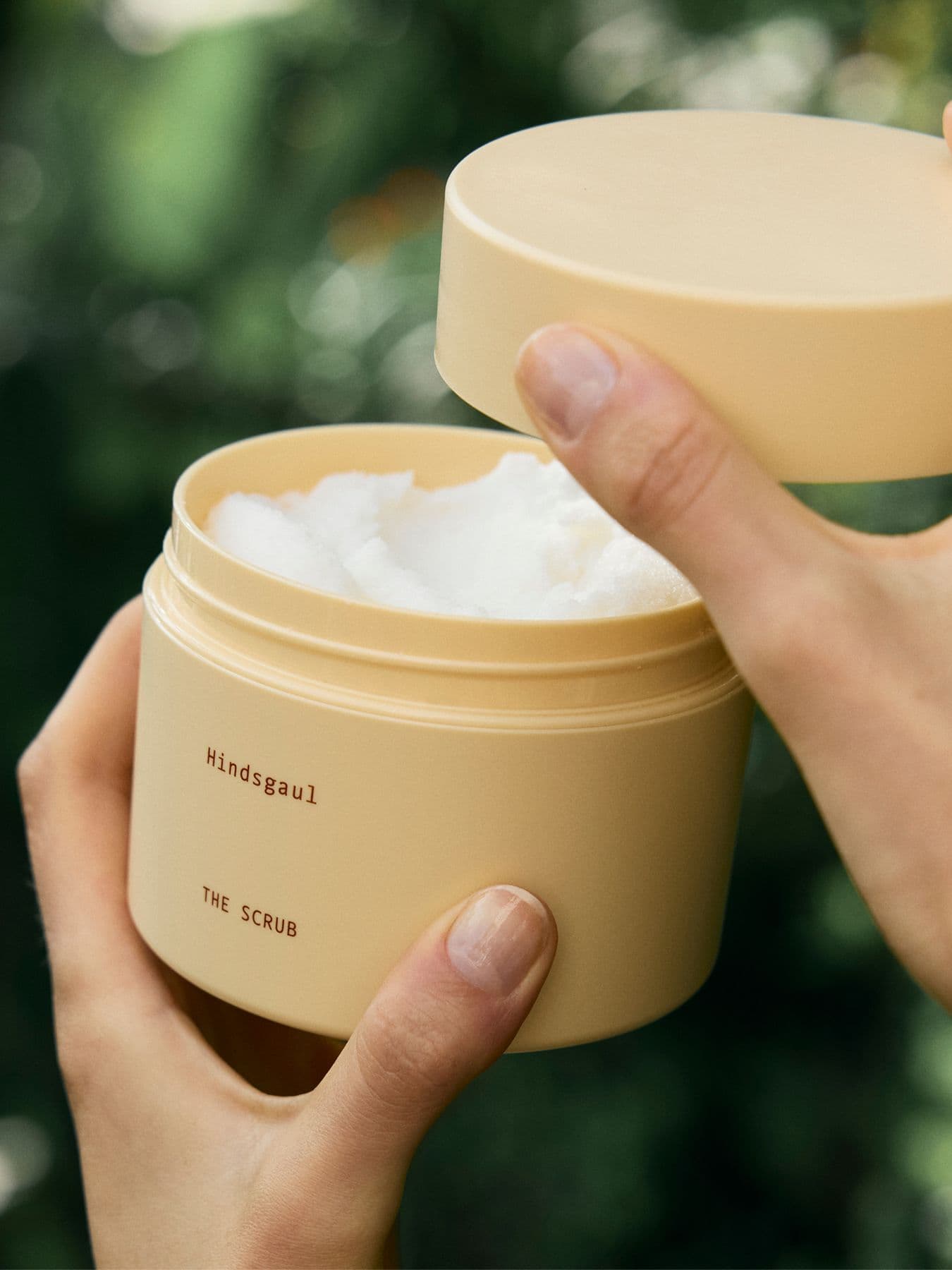 An up-close image of a model's hands as they open the Hindsgaul Hair scrub shampoo