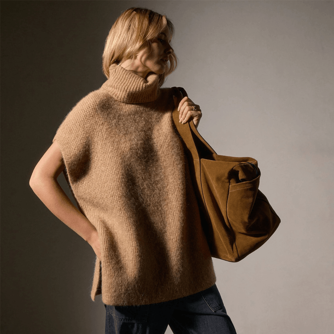 A model wears the Jame Perse Waffle Knit Funnel Neck Tunic carrying a big brown suede bag.