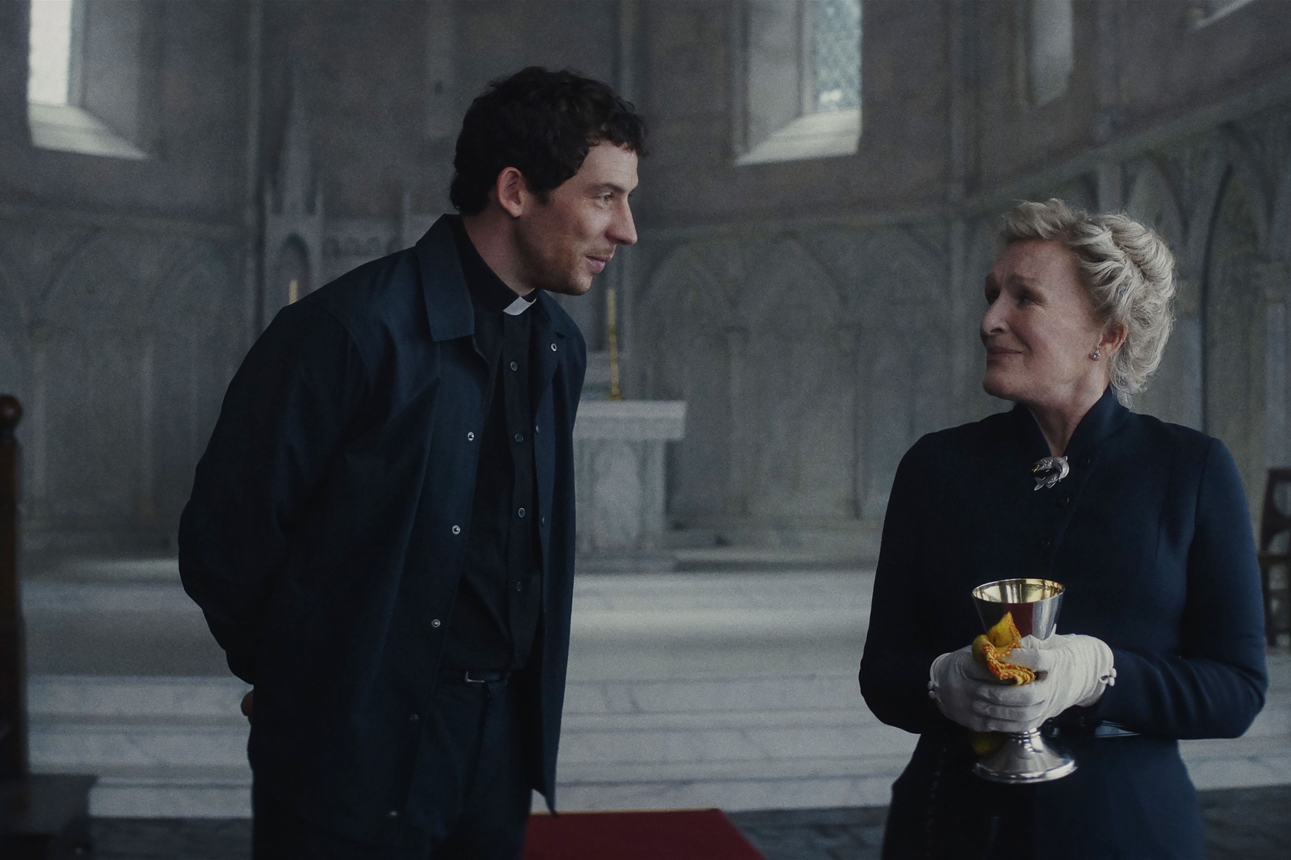 Actors Josh O'Connor and Glenn Close stand in a church in "Wake Up Dead Man: A Knives Out Mystery."