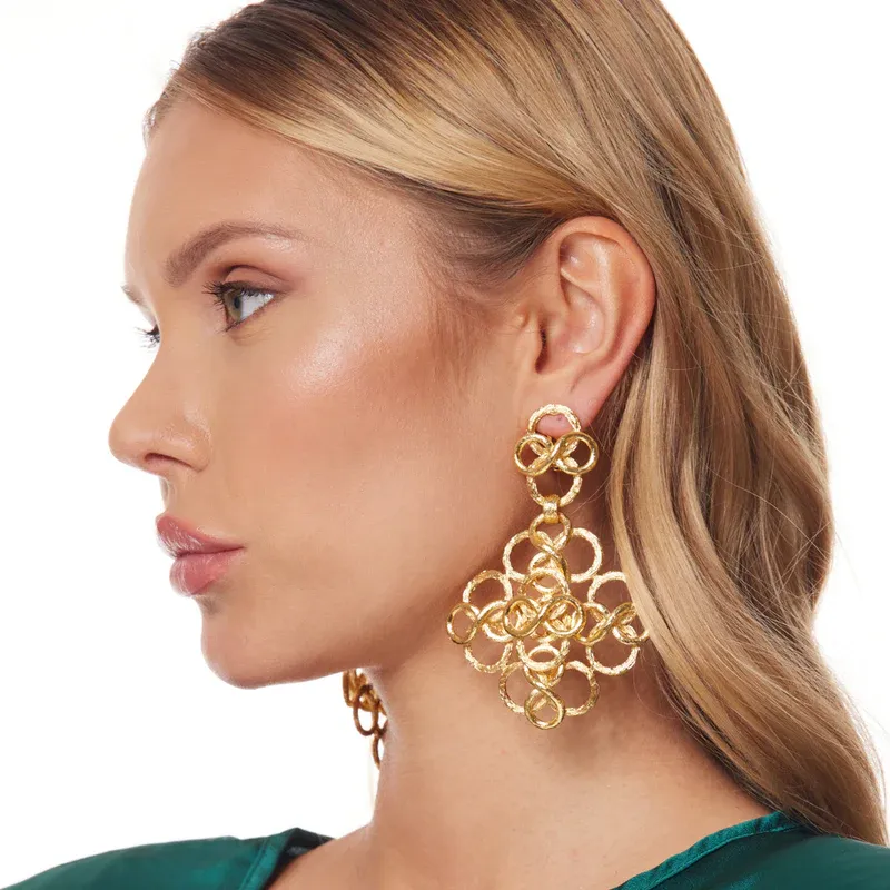 A blonde model wears gold Kenneth Jay Lane Fancy Swirl Clip Earrings
