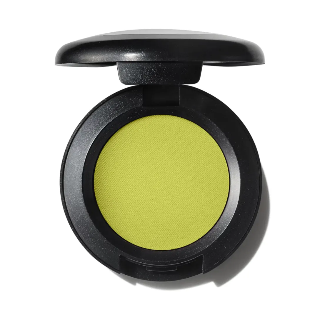 An open pot of MAC Eye Shadow in What's the Wifi, a light lime green, against a white background