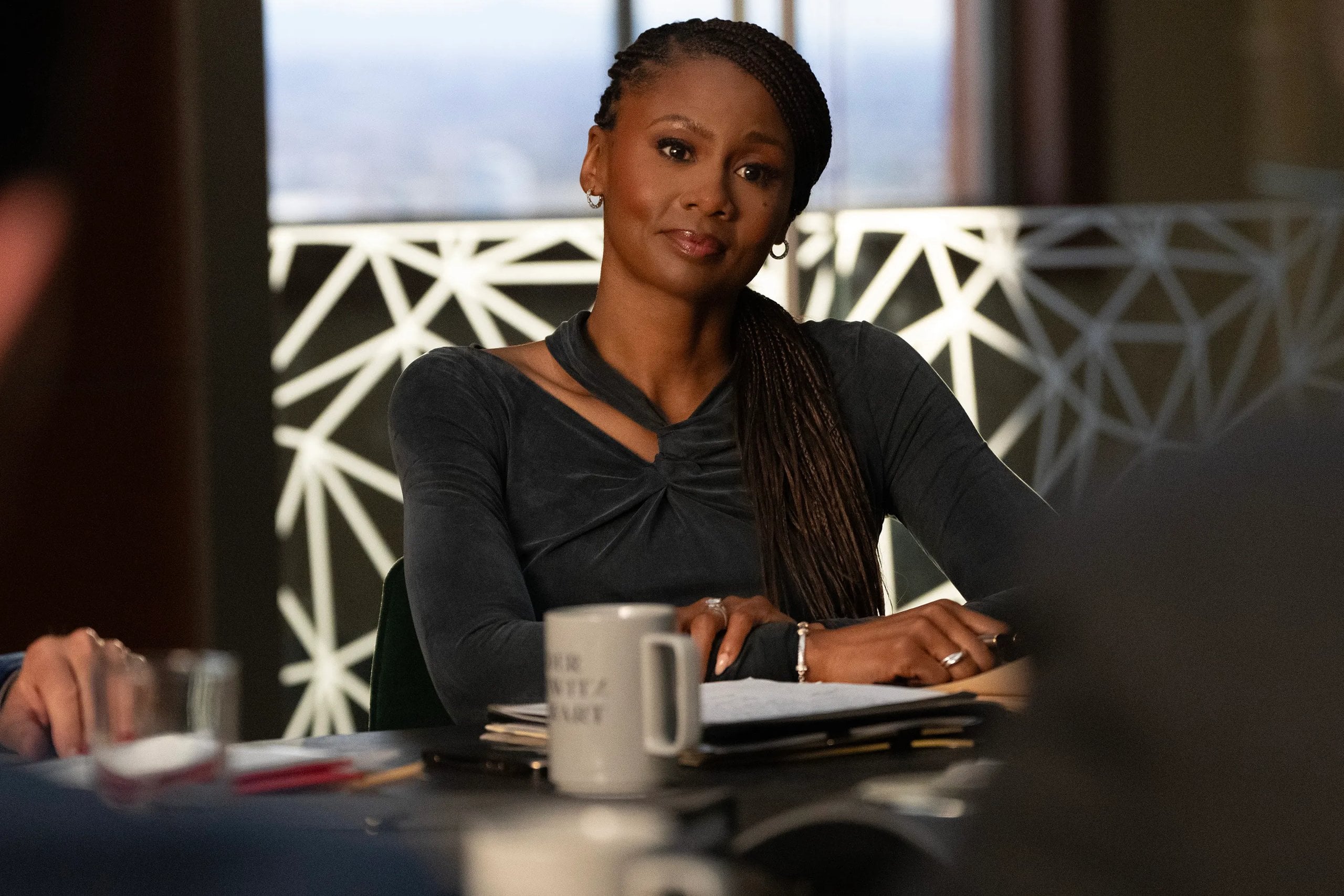 Actress Emayatzy Corinealdi sits at a desk in a still from "Reasonable Doubt."