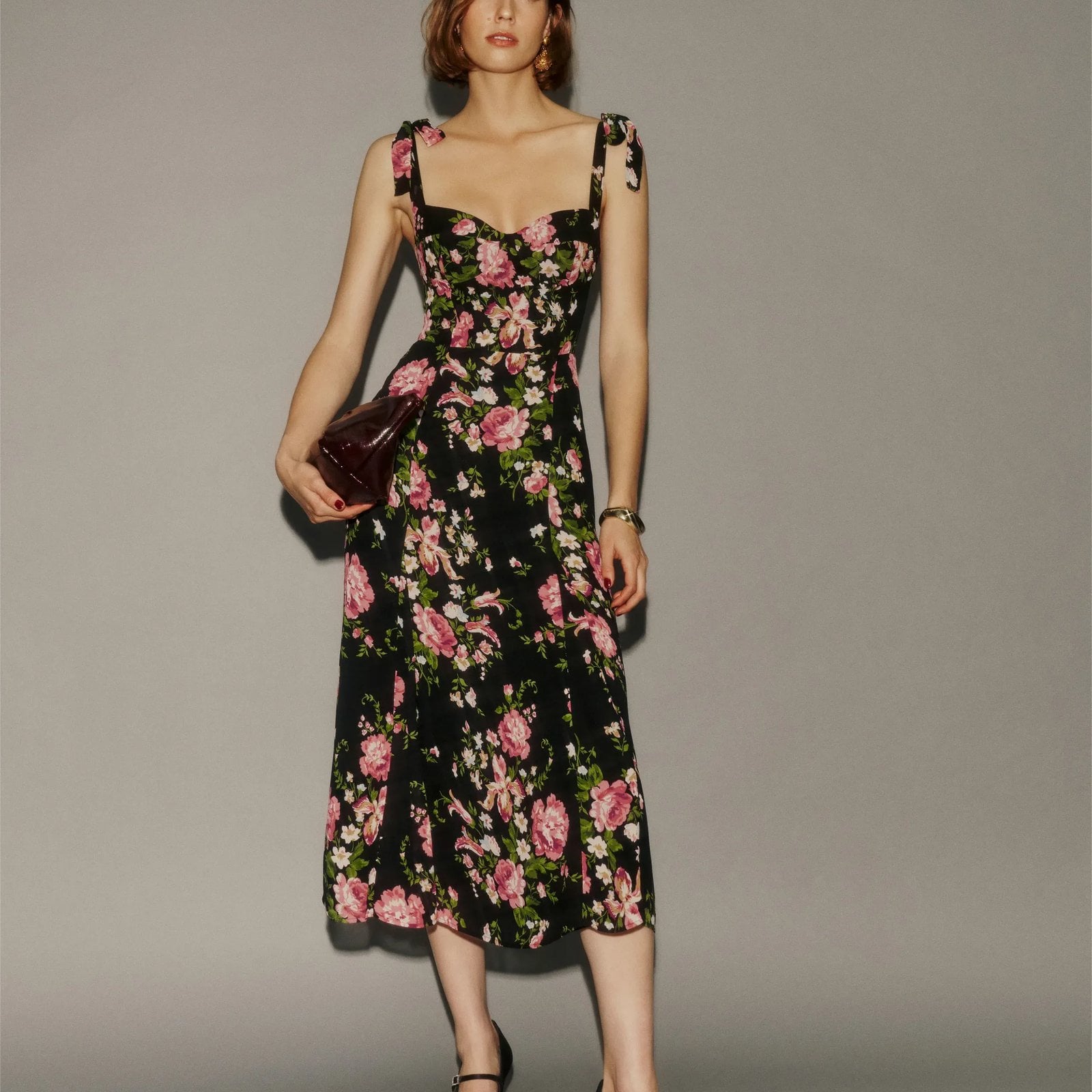 A woman in a black floral dress against a gray background