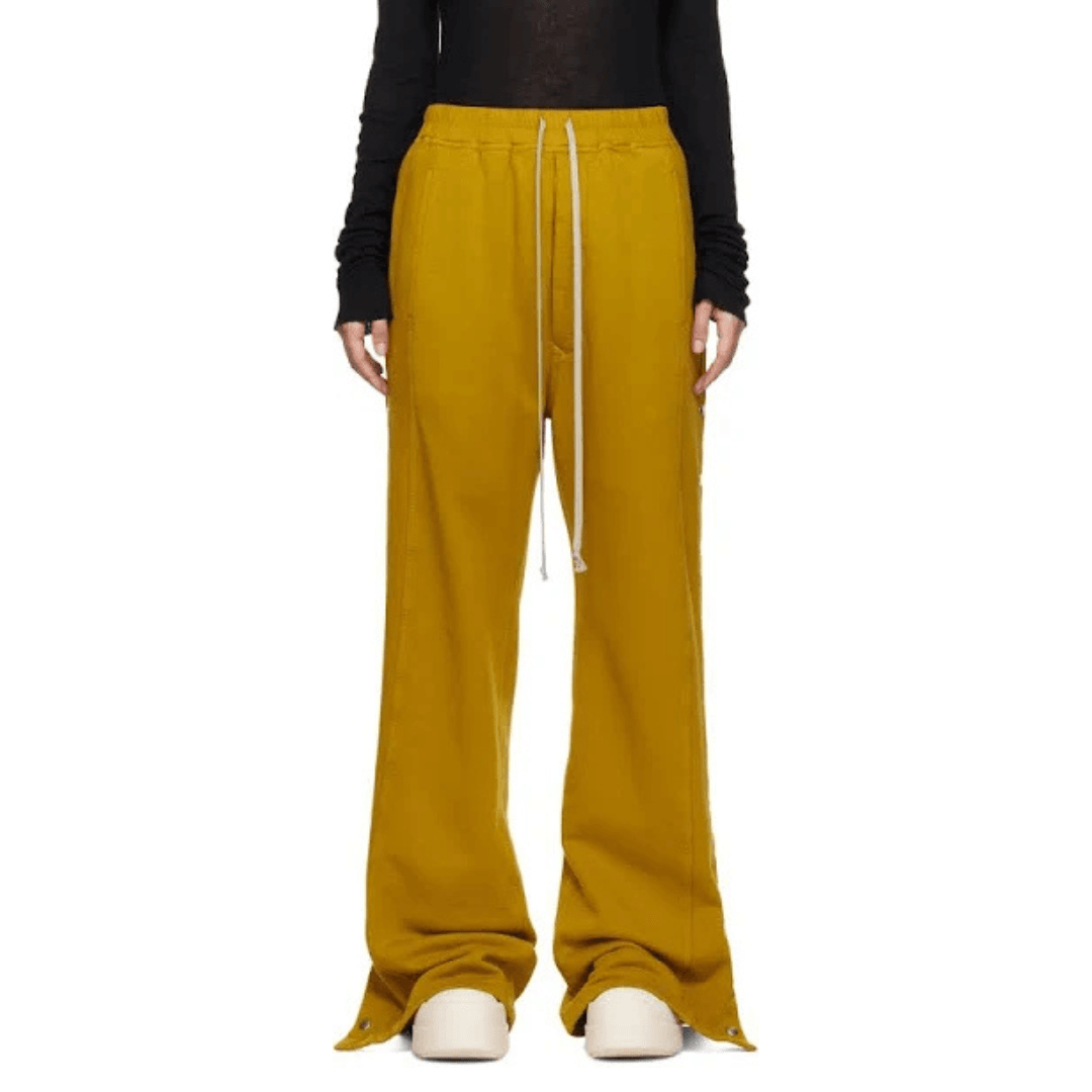 The bottom half of a model wearing the Rick Owens DRKSHDW Yellow Porterville Pusher Lounge Pants in a mustard yellow