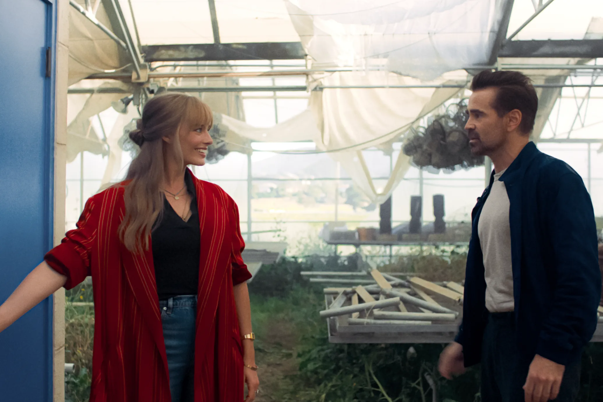 Margot Robbie and Colin Farrell smile at eachother while driving in a still from "A Big Bold Beautiful Journey."