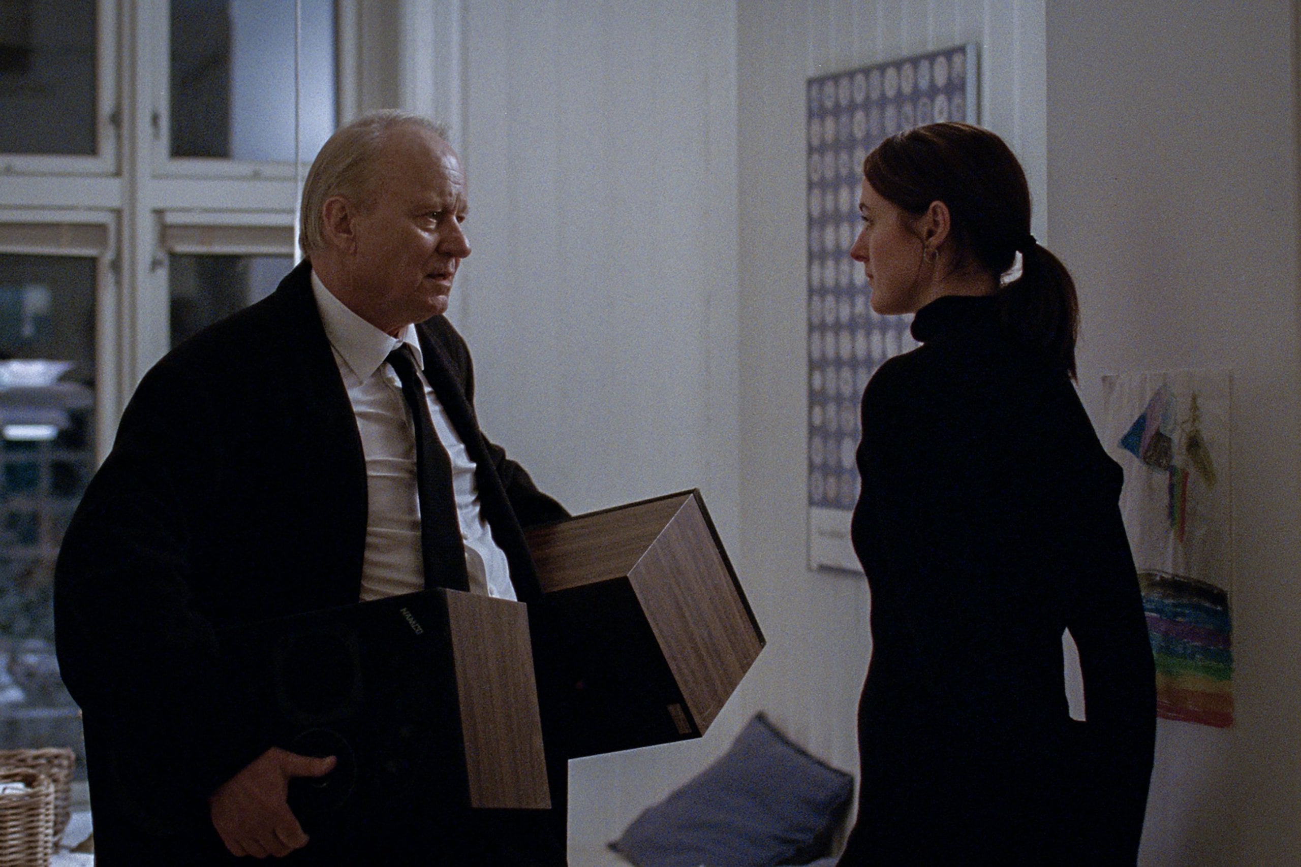 Stellan Skarsgård holding two boxes next to Renate Reinsve in "Sentimental Value."