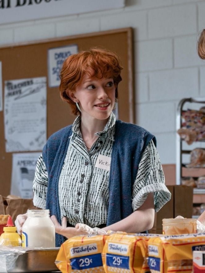Actors Amybeth McNulty and Maya Hawke stand together behind a table of groceries in a still from Stranger Things.