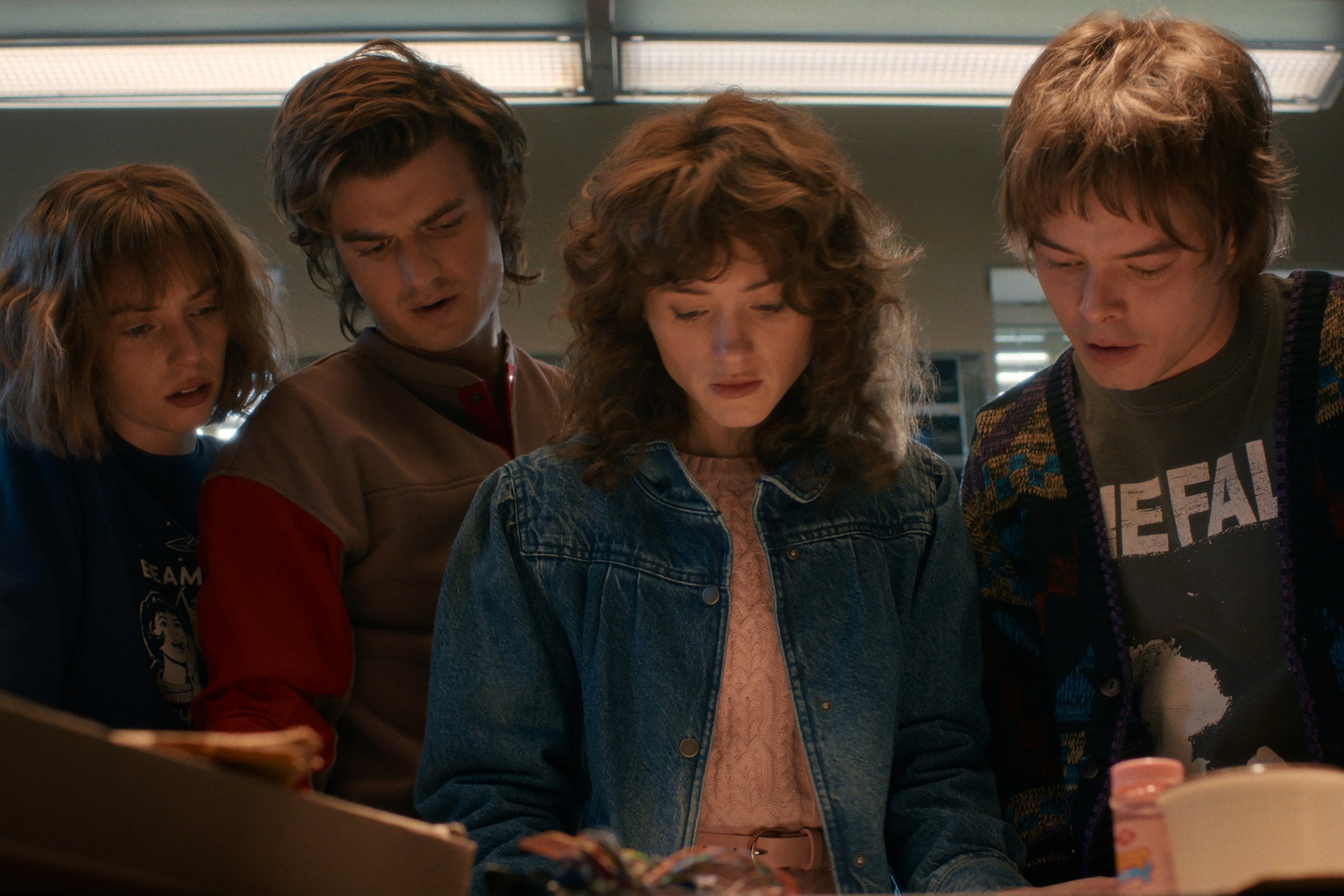 Actors Maya Hawke, Joe Keery, Natalia Dyer and Charlie Heaton standing over a table in "Stranger Things" season five