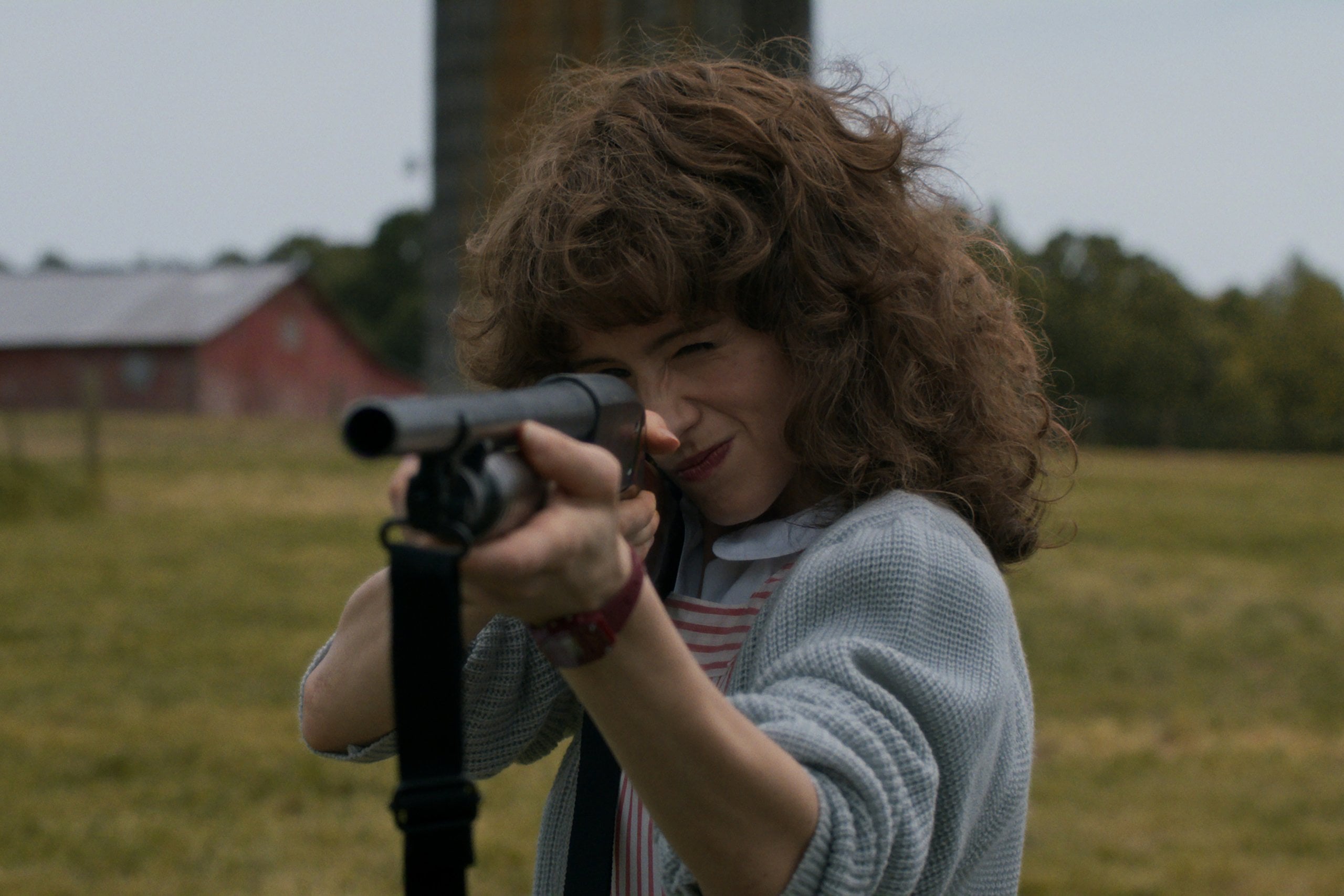Actress Natalia Dyer holds a shotgun as Nancy Wheeler in a still from Stranger Things.