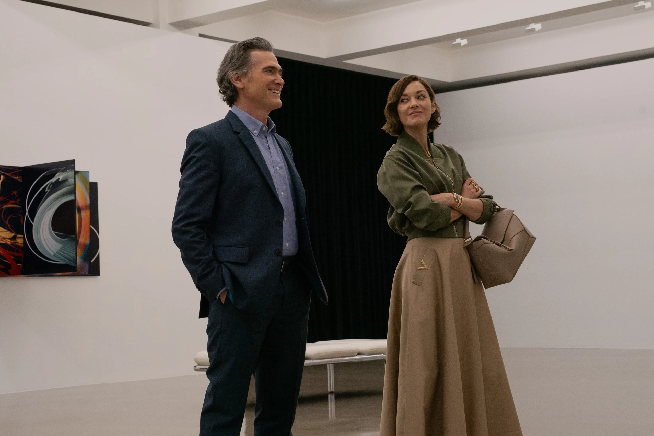 Billy Crudup and Marion Cotillard stand next two each other talking in a still from The Morning Show.