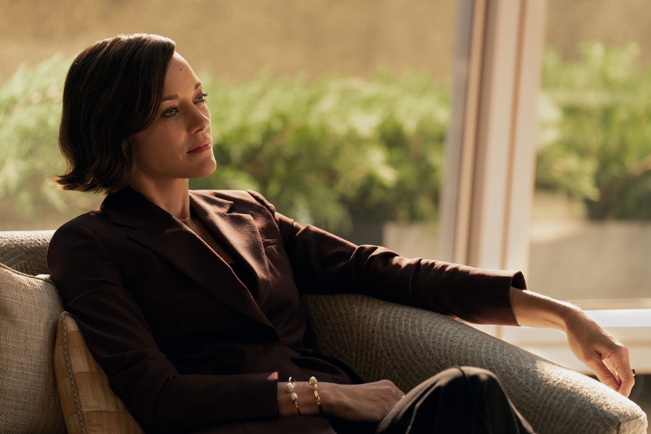Marion Cotillard sits on a chair in a still from The Morning Show.