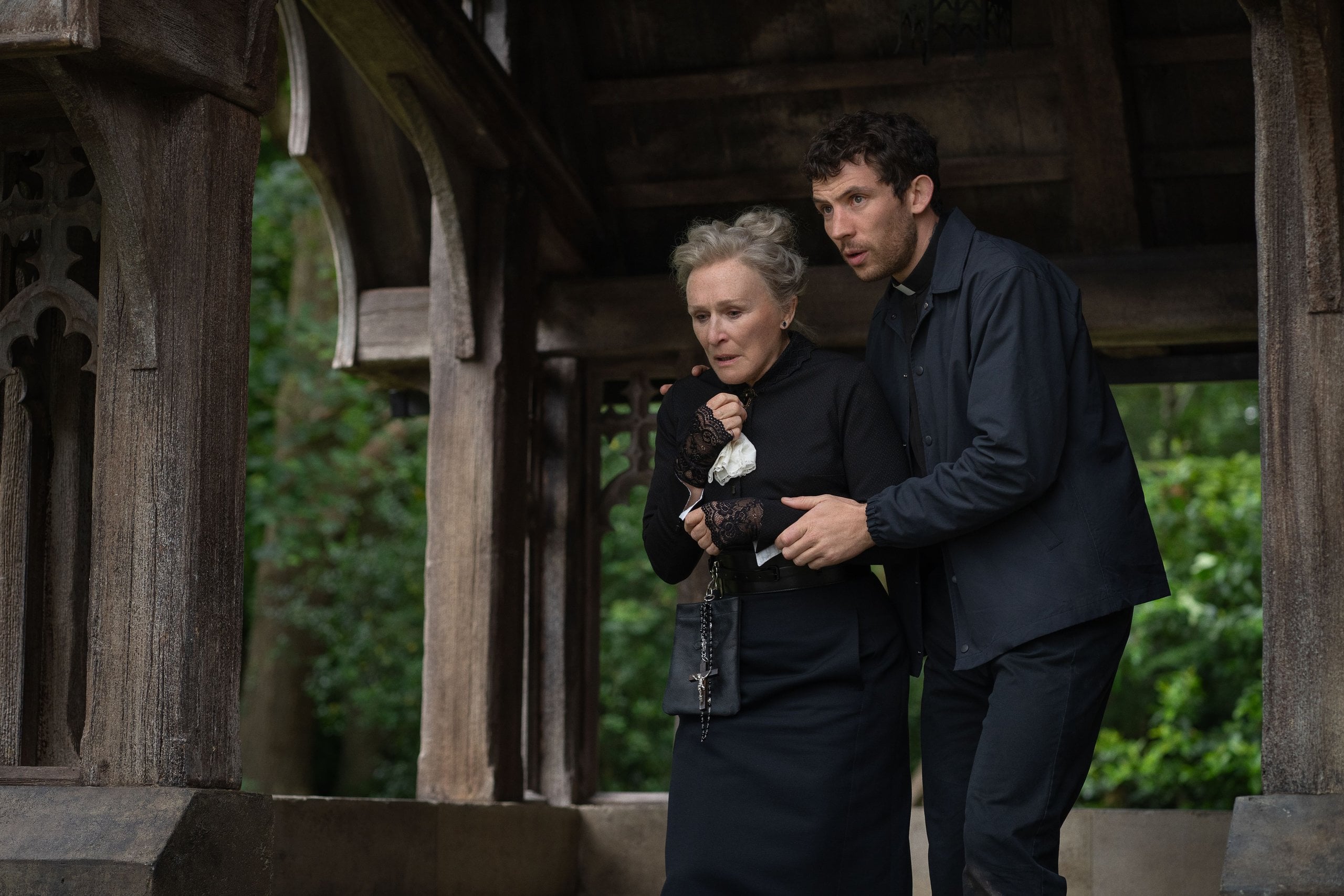 Actors Glenn Close and Josh O'Connor run from a chapel in a still from "Wake Up Dead Man: A Knives Out Mystery."