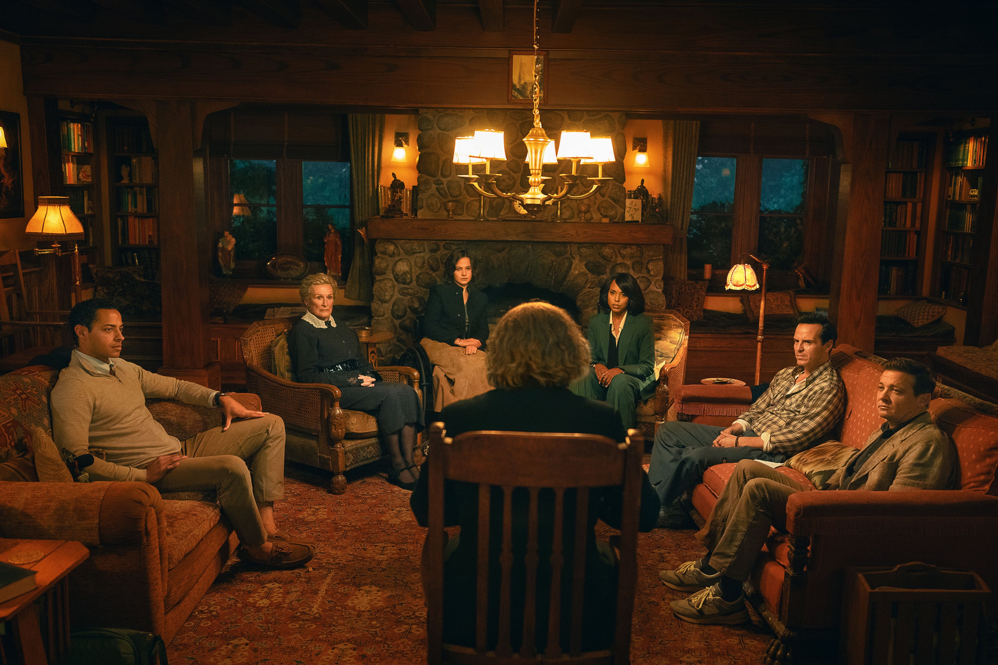 The cast of "Wake Up Dead Man: A Knives Out Mystery: sit around a candleit living room.