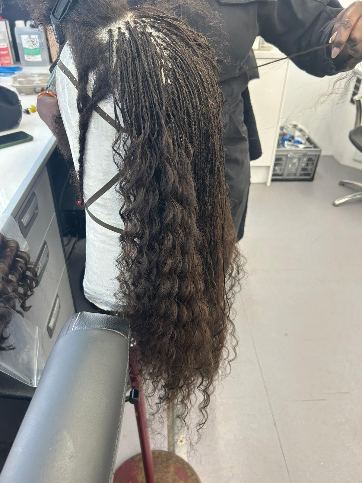 Braider Lorraine Dublin in the process of micro-braiding one of Elphaba's wigs in Wicked: For Good.
