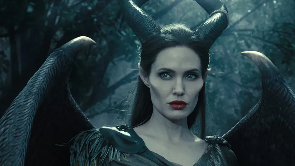 Angelina Jolie as Maleficent in a film from the movie, she's wearing horns and has exaggerated cheekbones.