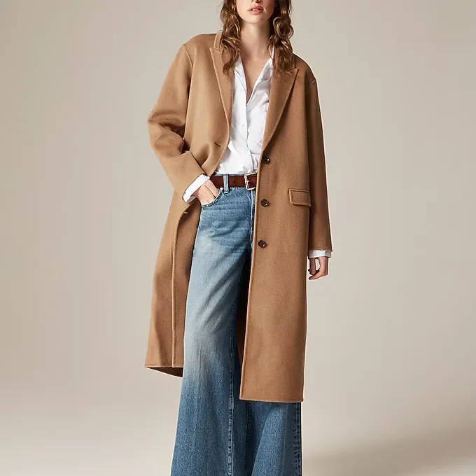 A model wearing the J.Crew Chiara topcoat in Italian double face in a camel color with a white top and jeans