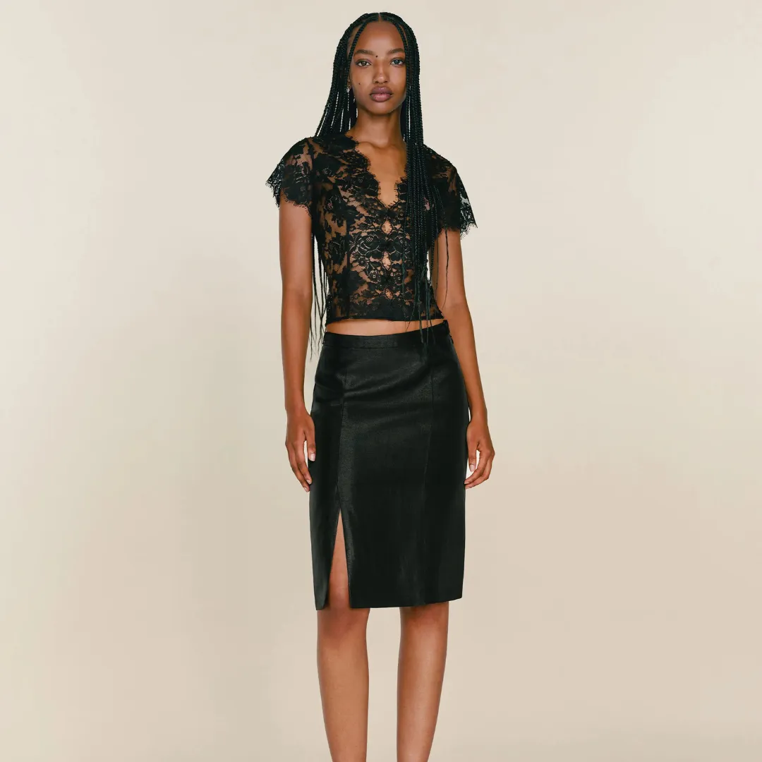 A model wears a faux black leather Reformation Victoria Skirt with side slit