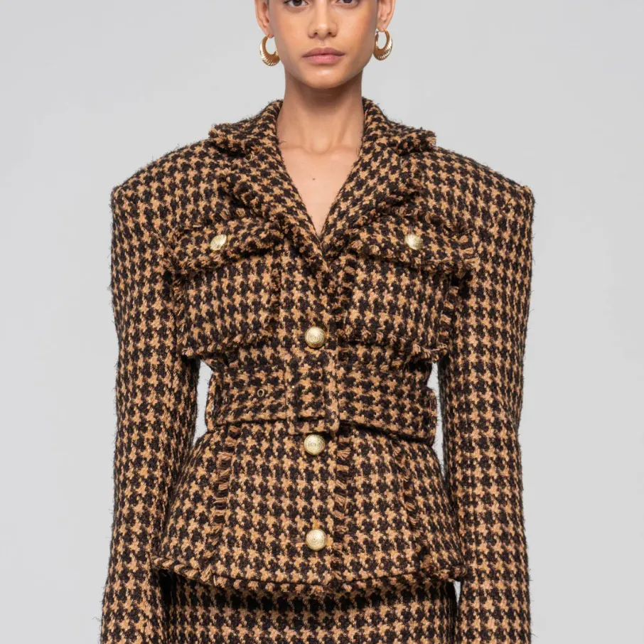 A models wears the Ronny Kobo Janice Jacket, a camel-and-black houndstooth jacket with wide shoulders and thick belt