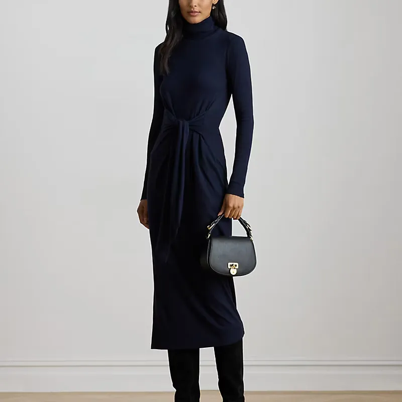 A model leans wears the navy blue Lauren Ralph Lauren Tie-Front Turtleneck Dress